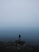 man standing on rock near body of water