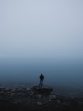 man standing on rock near body of water