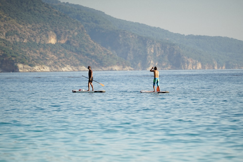 two men boat paddling on body of water