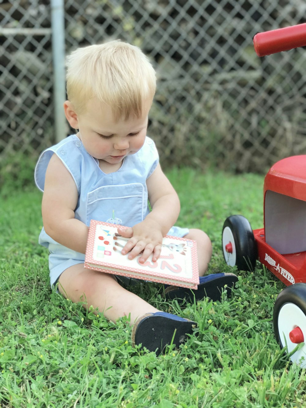 toddler sitting on grass during day