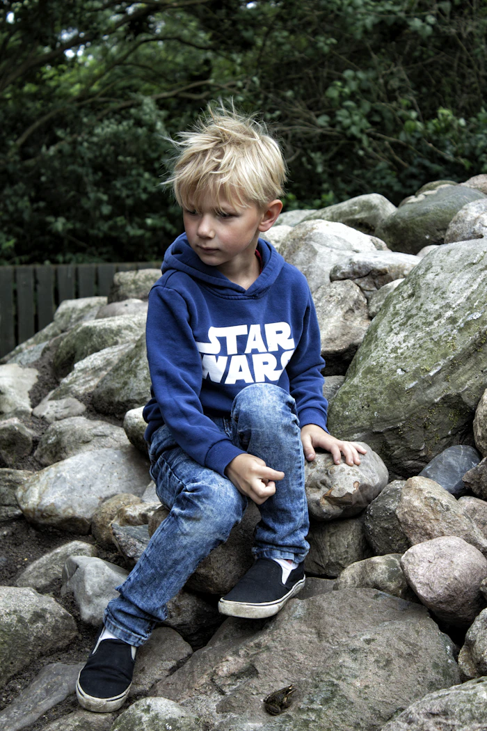 Boy sitting on rocks wearing a casual tee