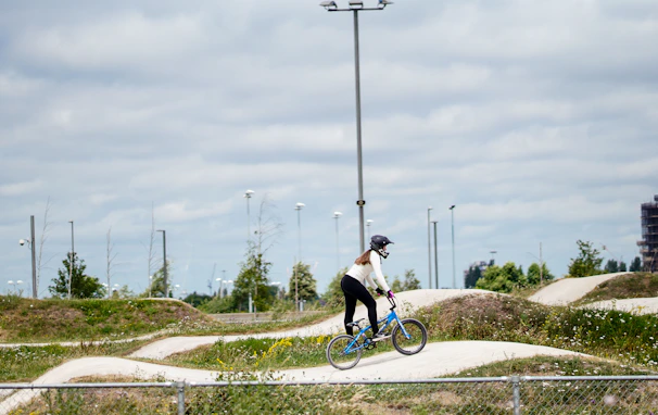 Wide shot of the Ruckstrack BMX track with riders practicing under purple and green lights.
