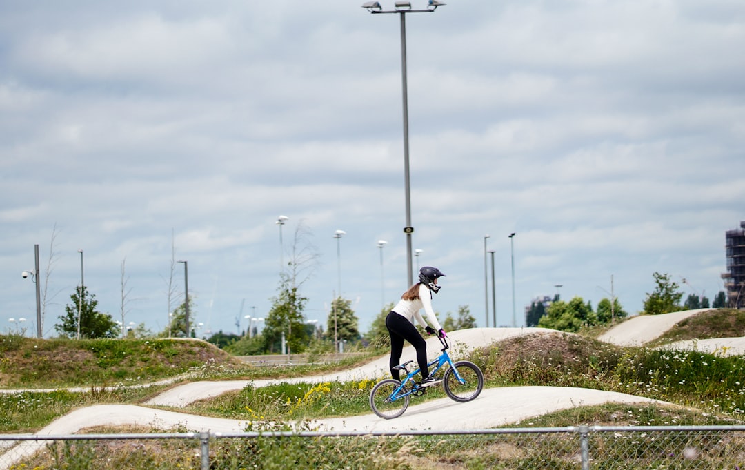 person riding blue bicycle on white pathway