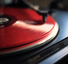 Close-up of a sleek black turntable spinning a vinyl record in a minimalist setting.