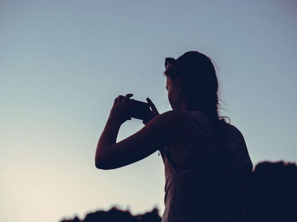 silhouette of woman taking photo of sunrise