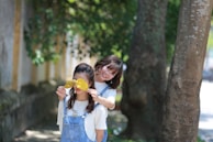 Two young girls playing joyfully in a sunny backyard.