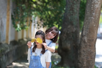 Two young girls playing joyfully in a sunny backyard.