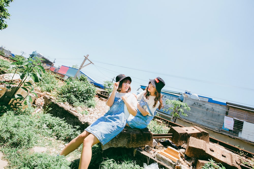 two women sitting on debris during daytime