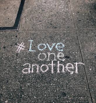 love one another chalk written on concrete floor