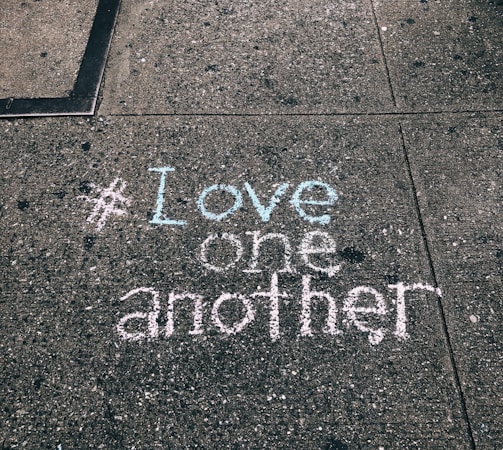 love one another chalk written on concrete floor
