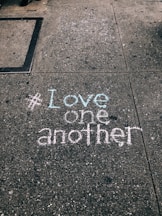 love one another chalk written on concrete floor