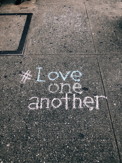 love one another chalk written on concrete floor