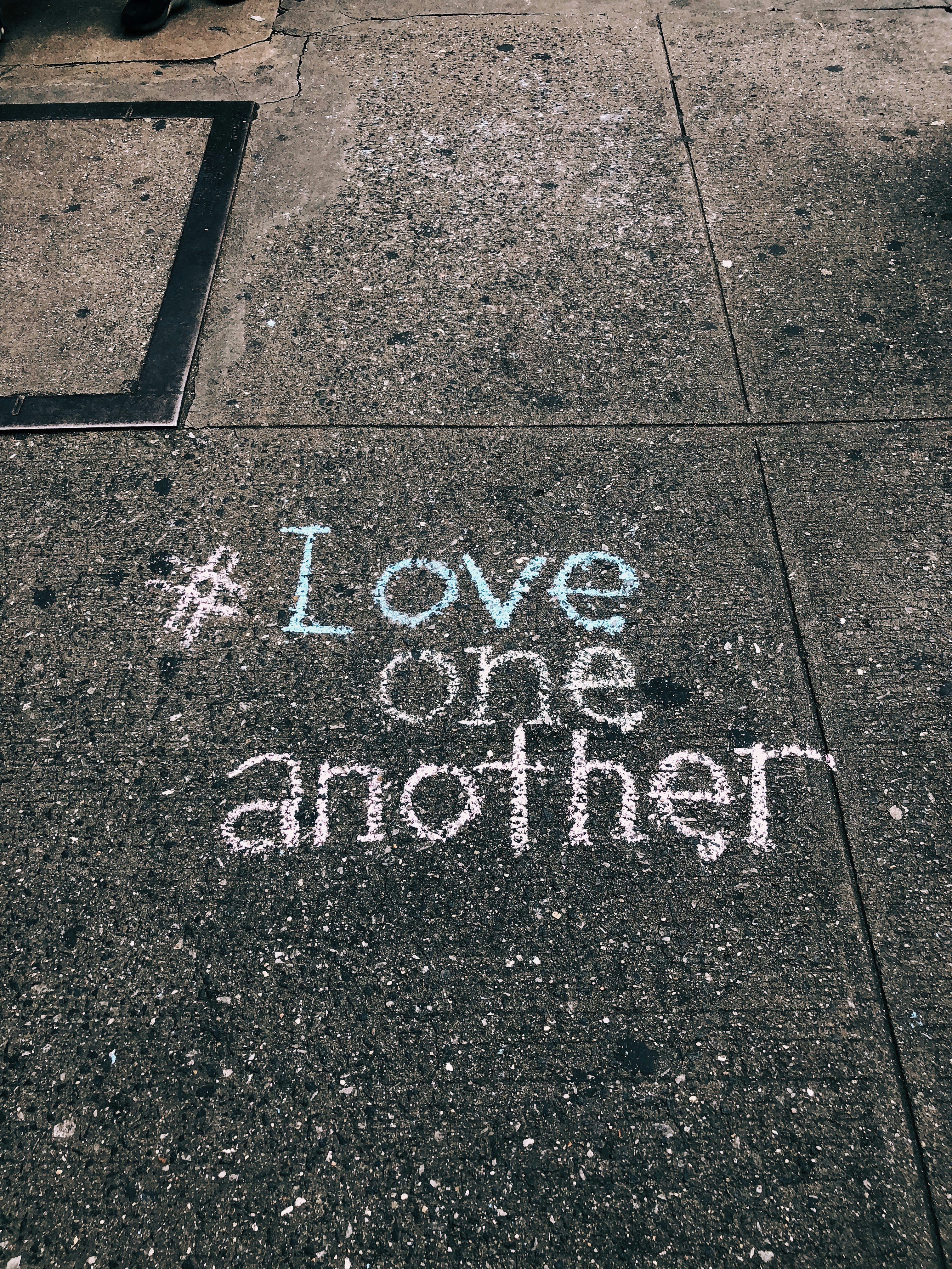 love one another chalk written on concrete floor