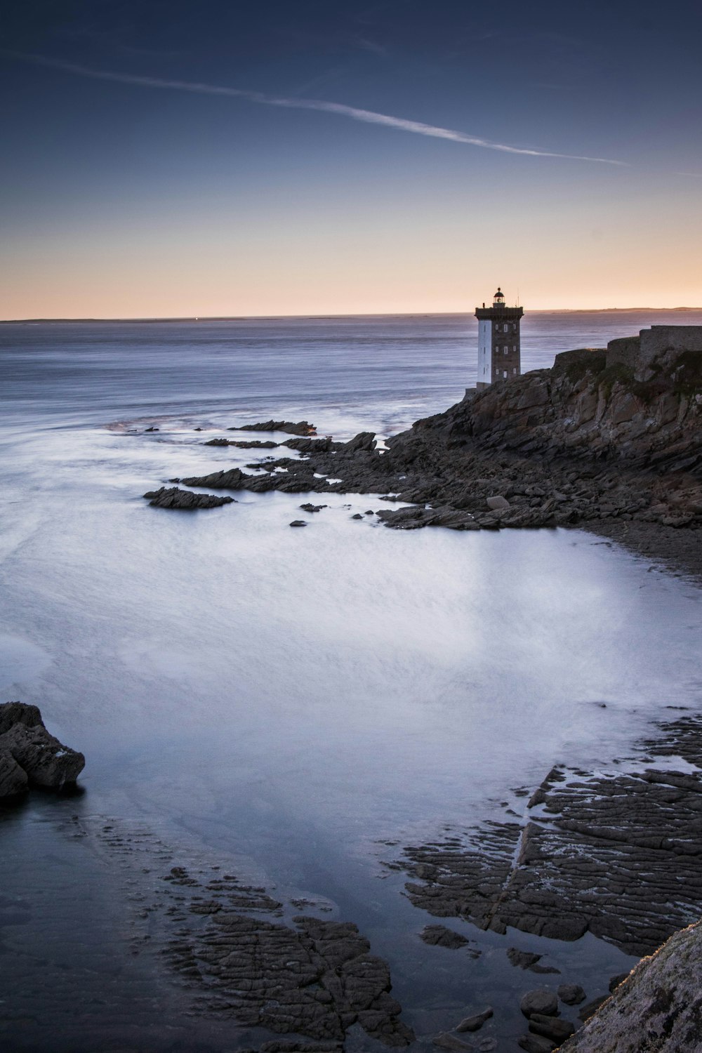 lighthouse near body of water during low tide