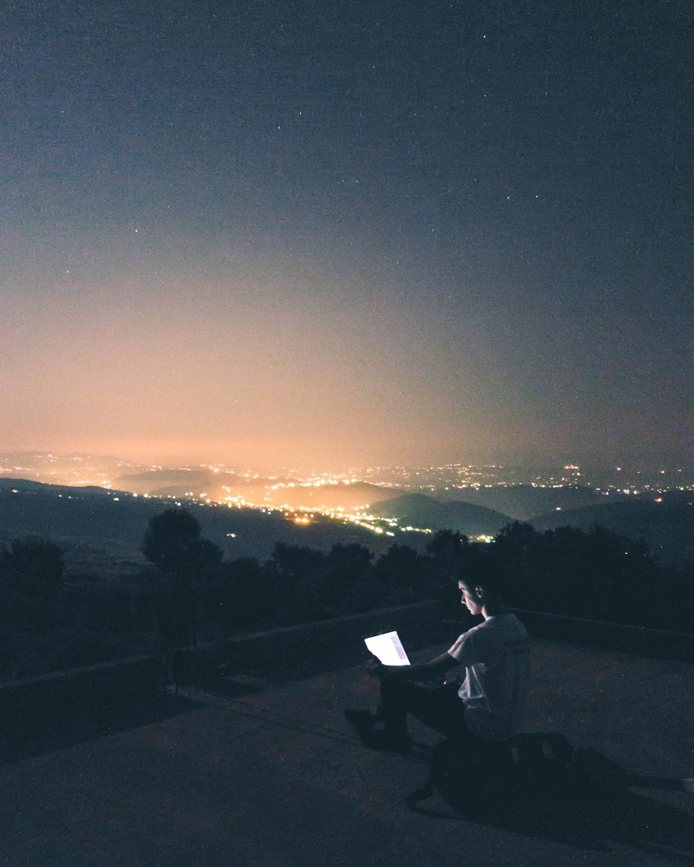 um homem sentado em cima de um banco à noite