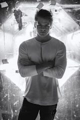 A determined actor standing tall on stage, arms crossed confidently.