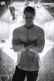 Editorial shot of a man in a classic white shirt standing against a muted pastel background.