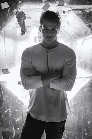 A confident male model in a stylish outfit illuminated by studio lighting.