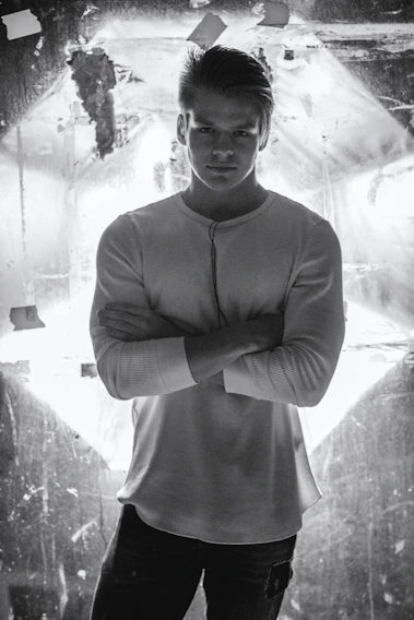 A close-up of a man wearing a soft, breathable Manmera premium t-shirt, standing confidently against a minimalist white background.