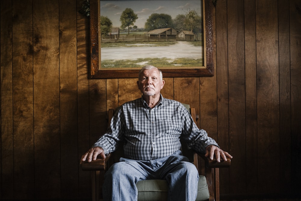 man sitting on armchair beside photo frame