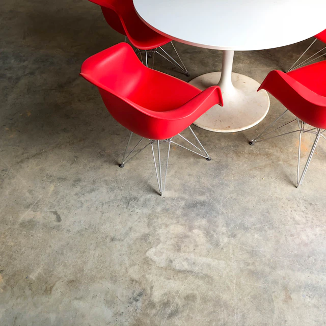 Red plastic chairs around a white pedestal table in a food hall