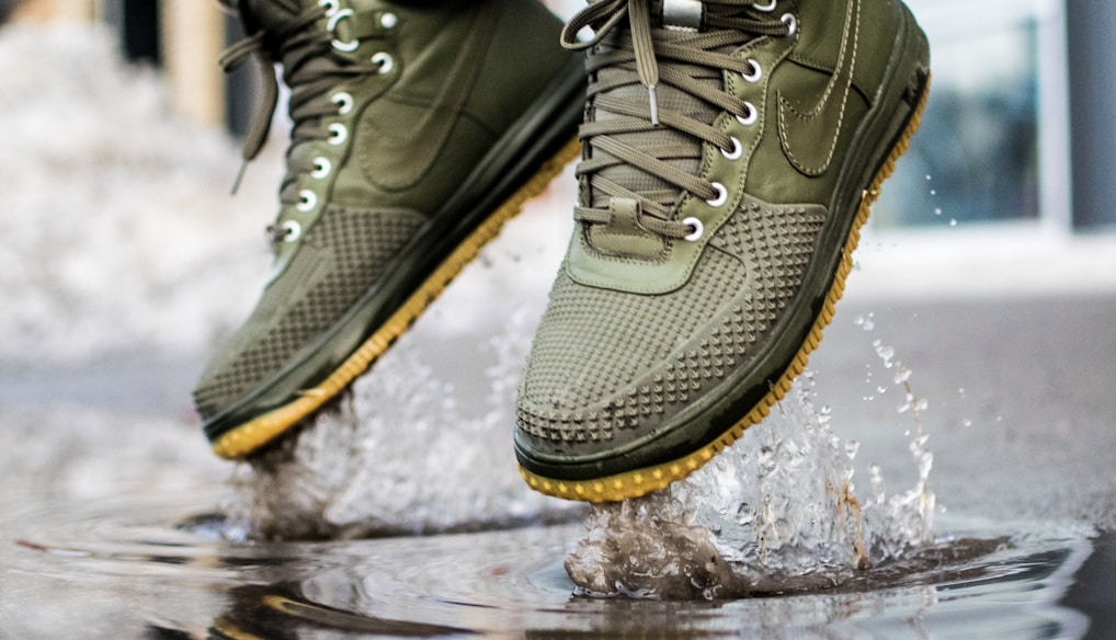 person wearing green Nike sneakers jumping on water