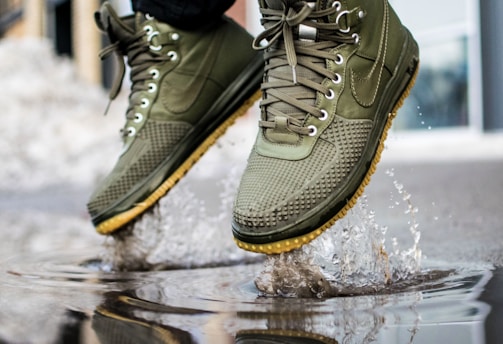 person wearing green Nike sneakers jumping on water