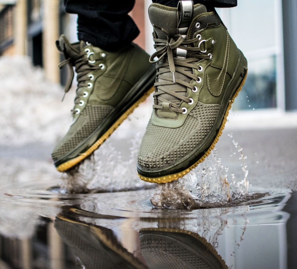 person wearing green Nike sneakers jumping on water