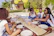A group of friends laughing and sharing plates of Toledo specialties outdoors.
