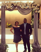 A bride and groom exchanging vows under a delicate floral arch with soft royal blue and silver accents