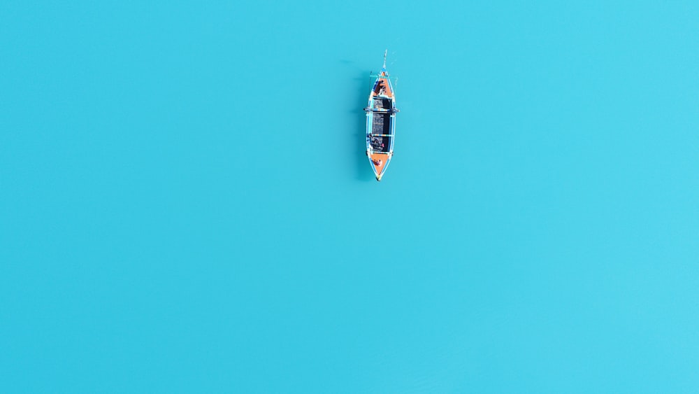 Photographie aérienne d’un canoë brun et bleu sur un plan d’eau