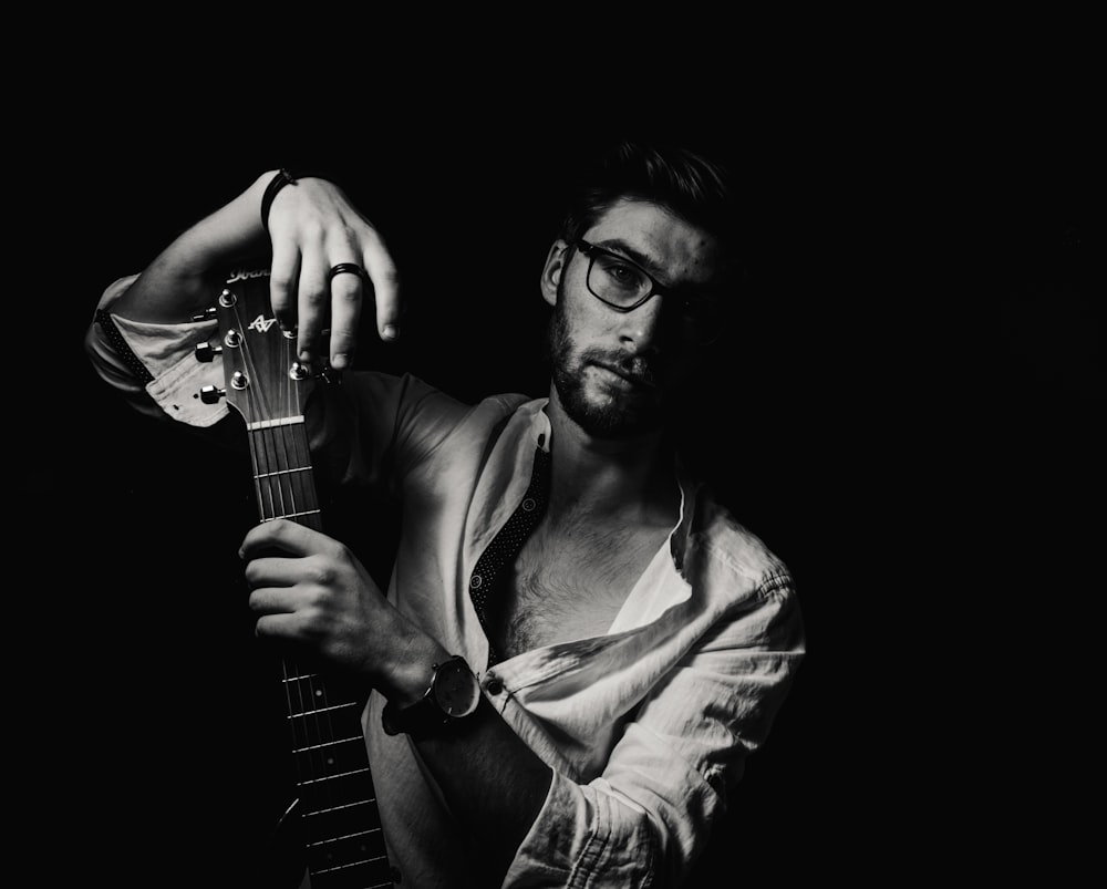 grayscale photo of man holding guitar