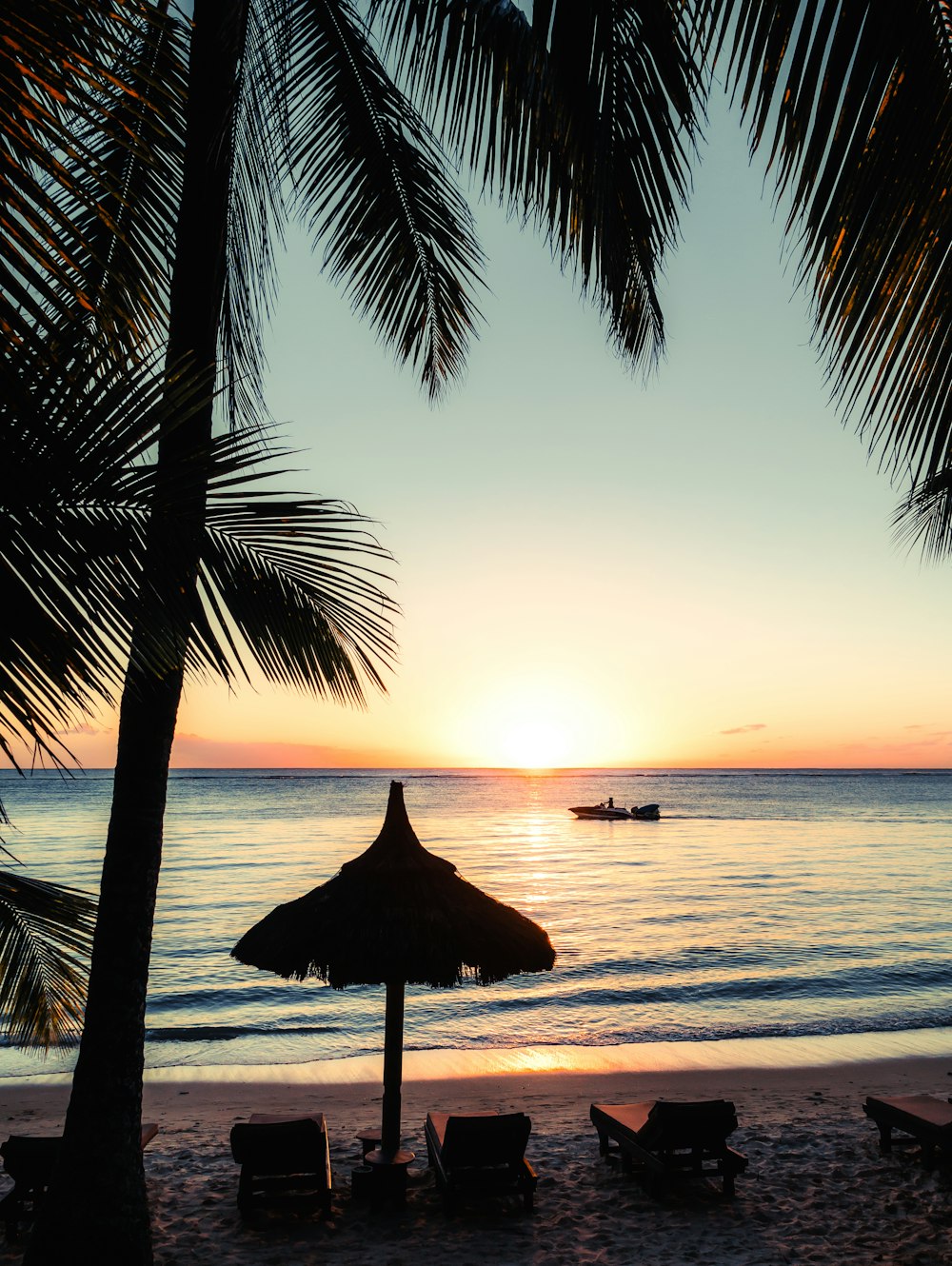 silhouette photo of boat near outdoor loungers