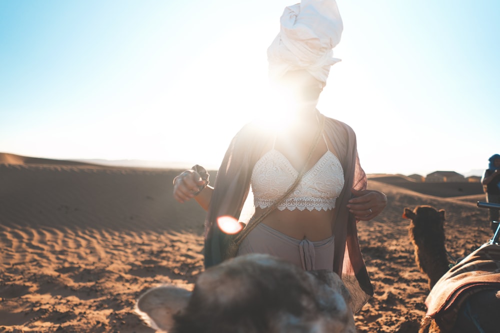 woman standing beside brown camel