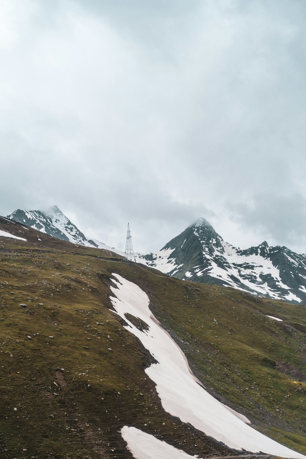 gray concrete tower on brown mountain under cloudy sky