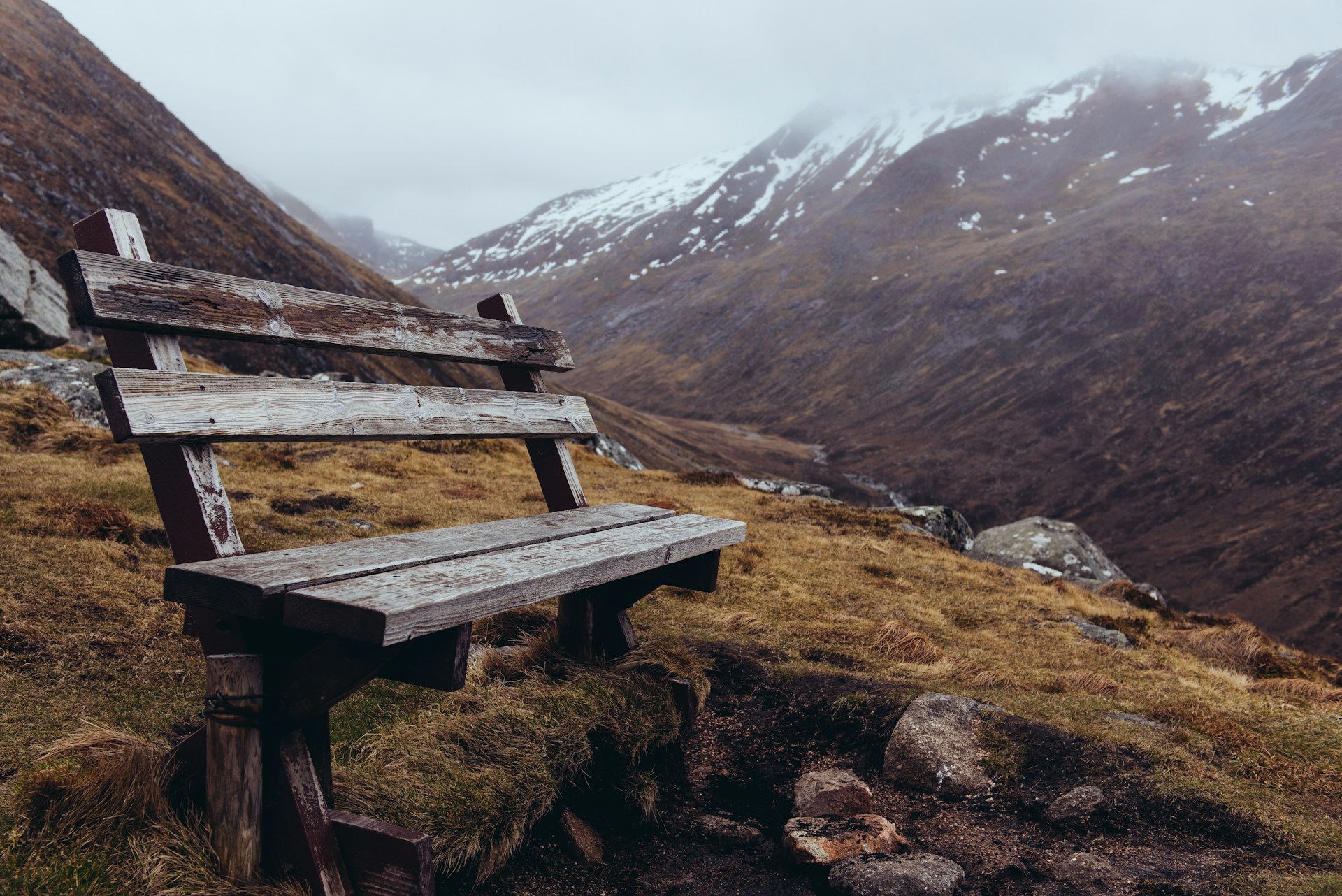 brown wooden bench on mountainside at daytime