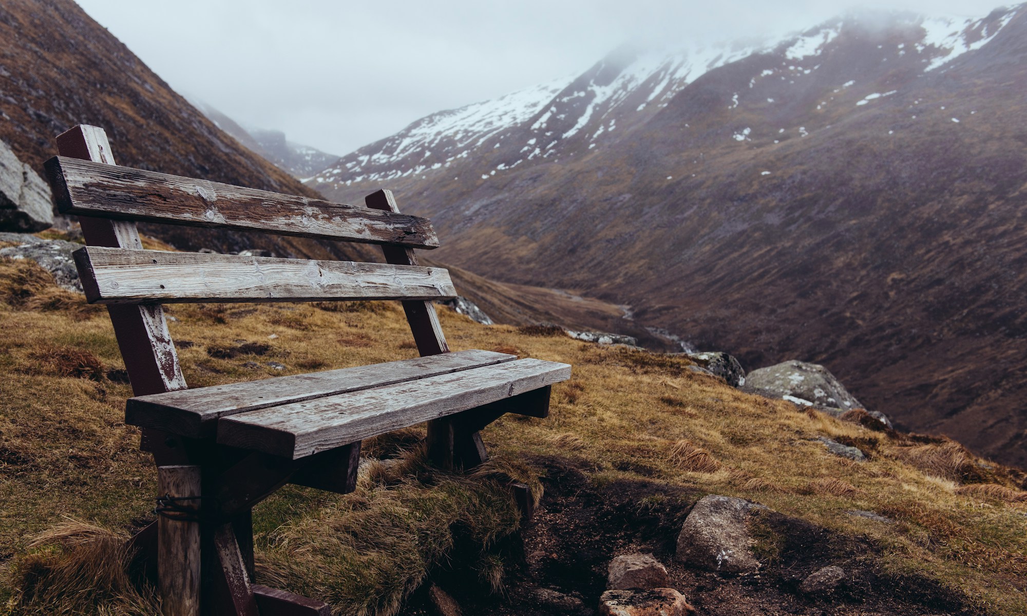 brown wooden bench on mountainside at daytime