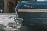 A bright red ’69 Nova with chrome rims parked under a glowing blue and red neon storefront sign.