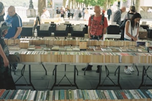 A customer browsing through a selection of rare books at a market stall