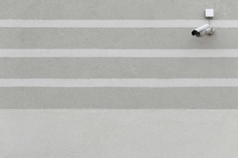 A series of horizontal stripes in light gray and green colors on a textured wall with a surveillance camera mounted on the upper right corner.