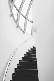 A sleek stairlift robot smoothly ascending a curved staircase in a bright home.