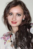 A smiling woman wearing a bold statement necklace and matching earrings at a party.