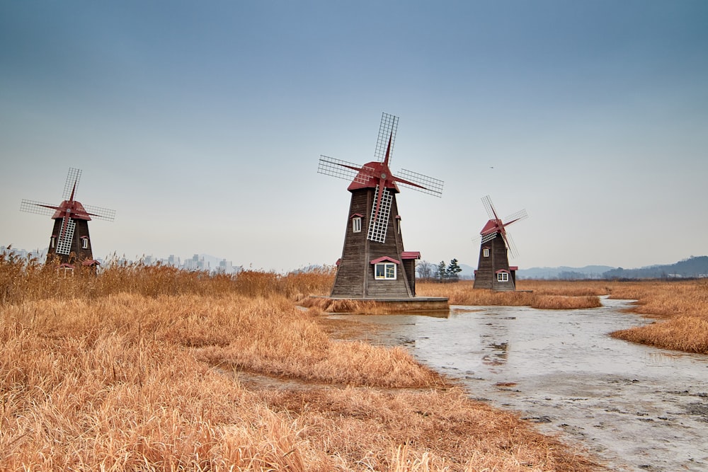 three brown windmills near river
