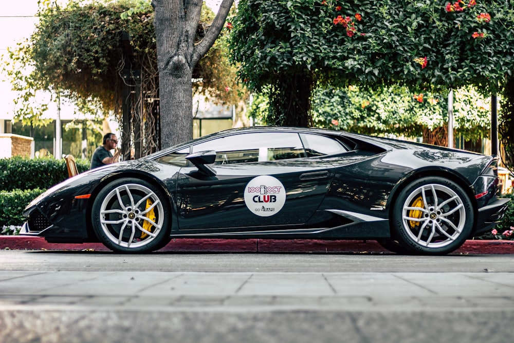 black Lamborghini parked near a sidewalk during day time