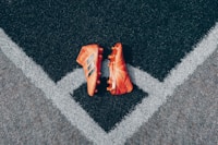 pair of orange adidas cleats on gray surface