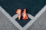 pair of orange adidas cleats on gray surface