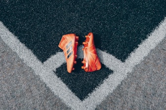 pair of orange adidas cleats on gray surface