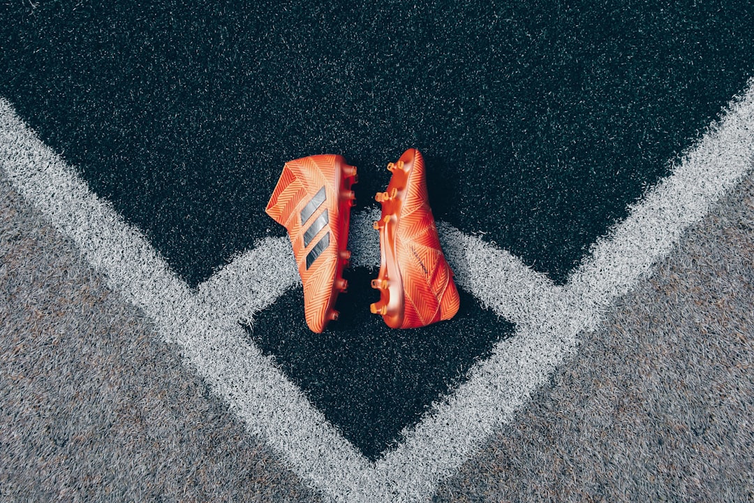 pair of orange adidas cleats on gray surface,