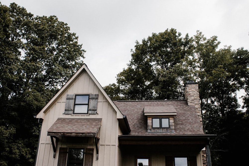 brown and white house surrounded by green leafed trees