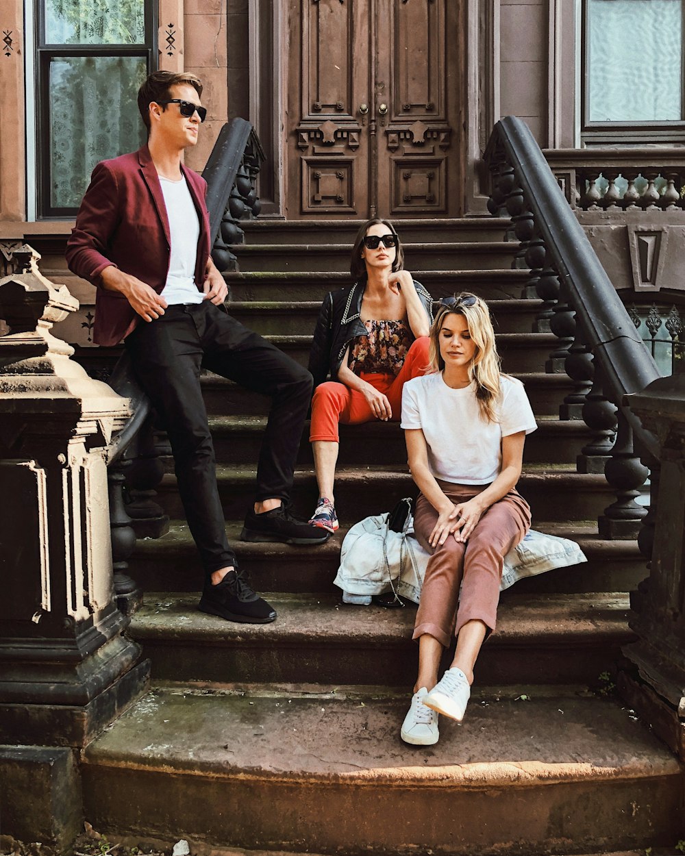 two women sitting and man standing on stair